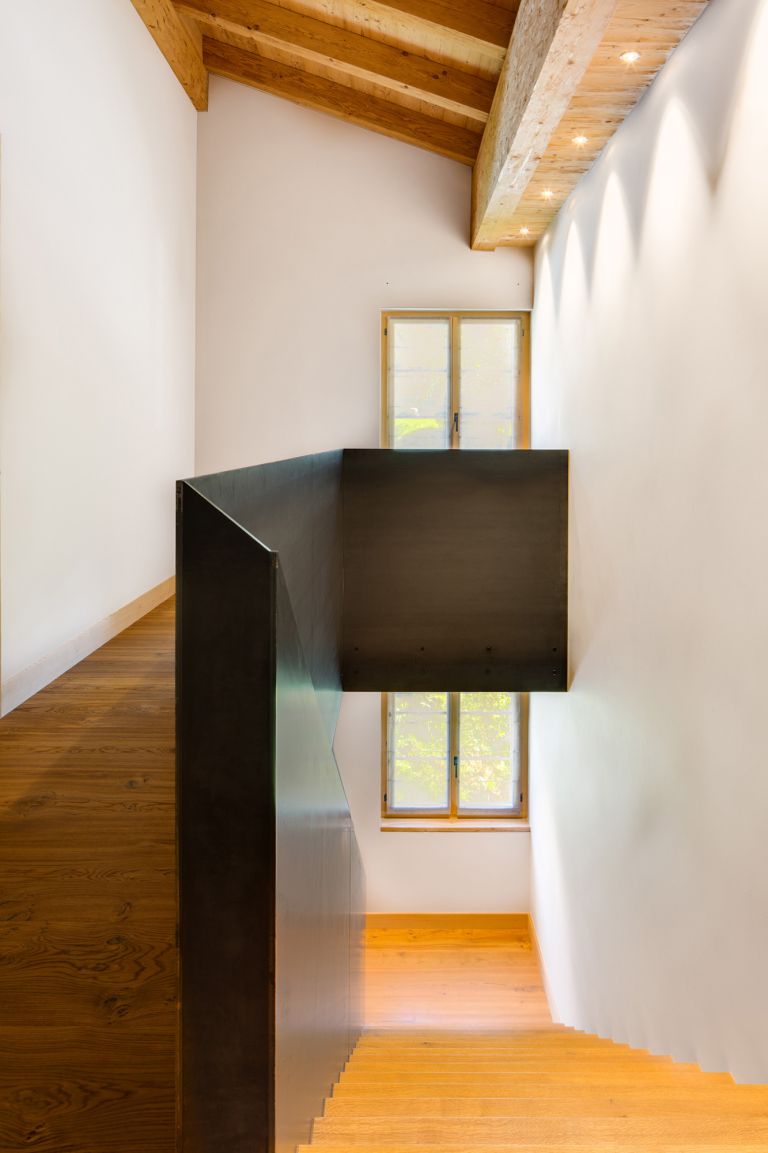 Klare Linien und Formen: Ein harmonisches Zusammenspiel von rohem Stahl, Holz und Licht im wohnungsinternen Treppenhaus.